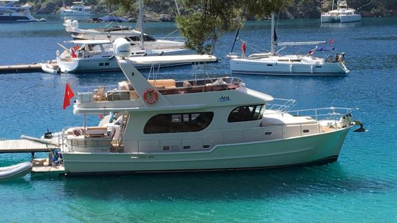 The trawler yacht Atıl is docked at the pier in Göcek, alongside other boats.