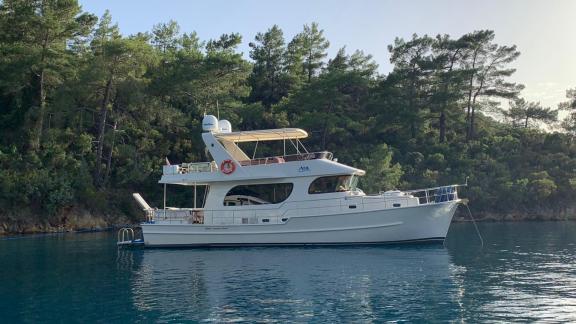 The trawler yacht Atıl is anchored in a quiet bay in Göcek.