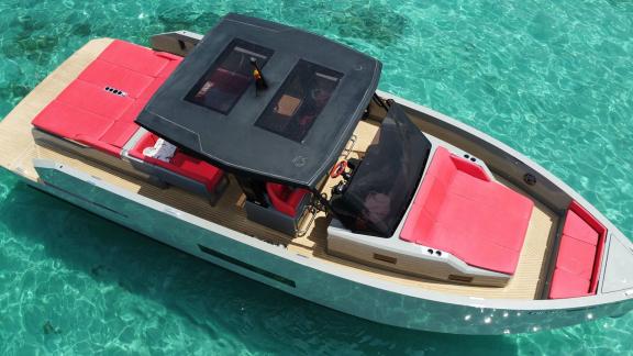 Die Motoryacht Aura bietet großzügige rote Sitzbereiche und ein modernes Design über türkisfarbenem Wasser.