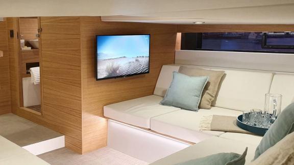 The living area of motor yacht Aura features comfortable seating and a modern TV, offering a stylish ambiance.