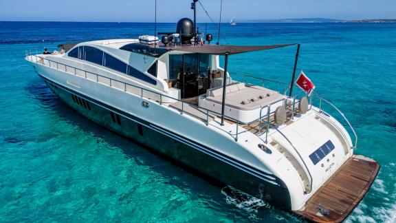 The motor yacht Aya One is peacefully anchored in clear turquoise waters.