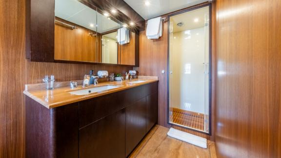 Das Badezimmer auf der Motoryacht Aya One bietet ein großzügiges Waschbecken und eine Glasdusche im modernen Design.