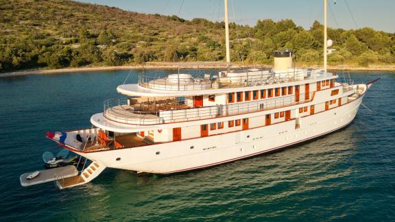 The Bellezza yacht anchored in a serene bay, surrounded by green hills and clear waters.