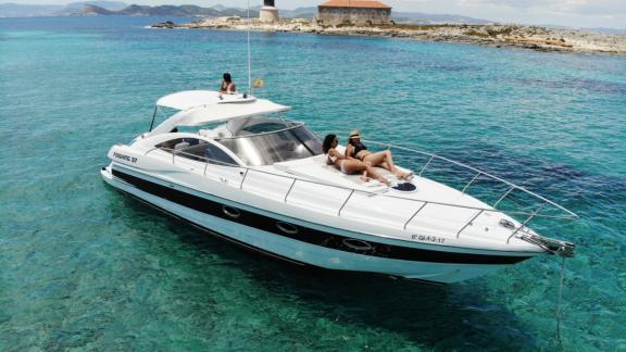 Guests sunbathing on the foredeck of motor yacht Black Ball, enjoying the turquoise waters.