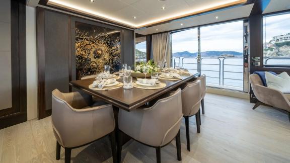 Among Spain yacht charter options Blue Infinity One shows indoor dining table with sea view.