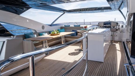 Among Spain yacht charter options Blue Infinity One shows upper deck with dining table and bar.