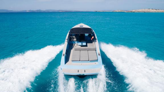 Die Blue Steel Motoryacht fährt schnell über türkisfarbenes Wasser.