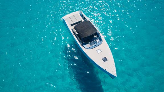 Die Blue Steel Motoryacht in kristallklarem türkisfarbenem Wasser, von oben fotografiert.