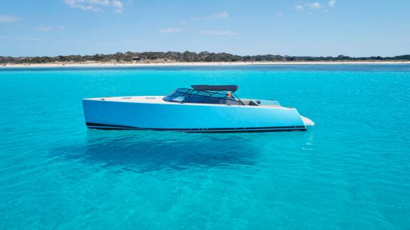 The Blue Steel motor yacht is anchored near the shore in turquoise waters.