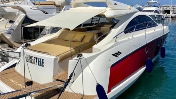 The aft deck of motor yacht Breathe features a shaded lounge area equipped with comfortable cushions.