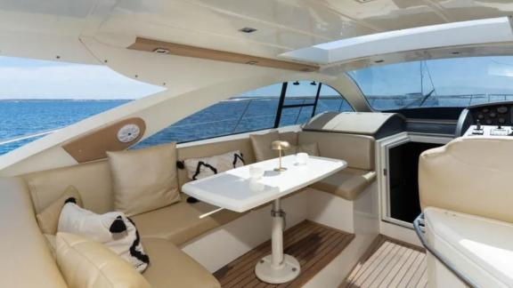 The open lounge area of motor yacht Breathe features comfortable seating and a table.