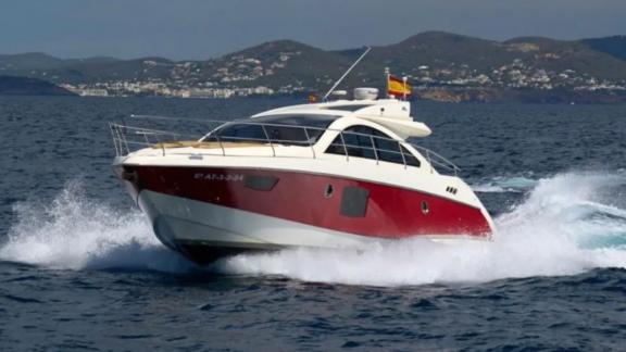 The motor yacht Breathe is cruising at high speed, standing out with its striking red hull.