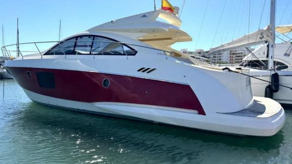 The motor yacht Breathe is anchored at the marina, standing out with its red and white hull.