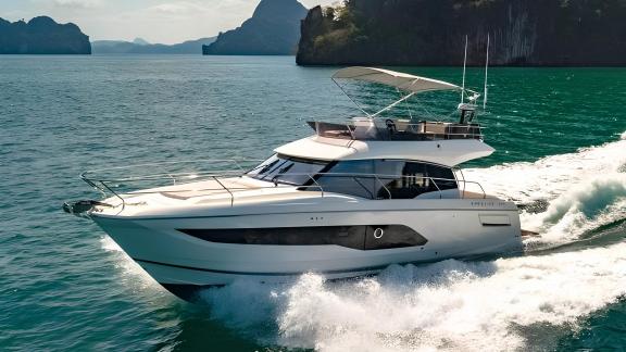 The motor yacht Brigadoon cruising fast on the sea, surrounded by green islands and blue waters.