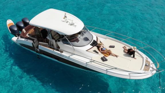 Guests sunbathe on the foredeck of the motor yacht Carmencita la Grande, enjoying the turquoise sea.