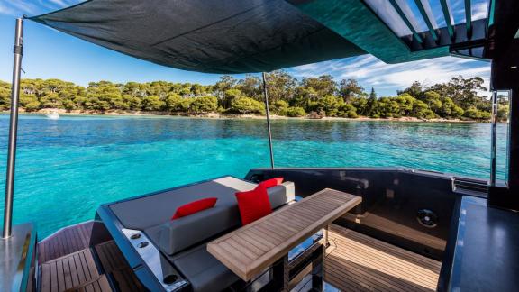 Among Monaco yacht charter options Cest Party motor yacht shows shaded seating with table and sea view.