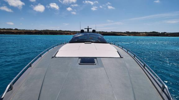 The wide foredeck of motor yacht Chilli is seen on calm sea under a clear blue sky.