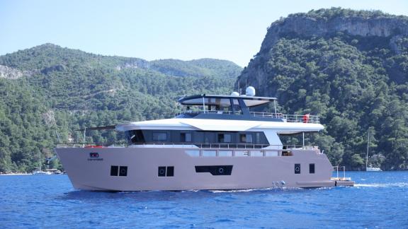 Compass trawler yatı, Göcek'in yeşil tepeleri arasında seyir halinde görülüyor.