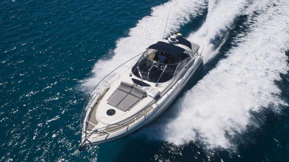 Die Motoryacht Com Tu fährt mit Tempo vor Ibiza Frontansicht auf See.