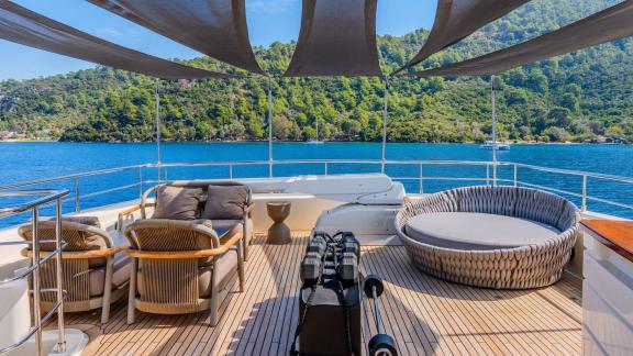 Ariela offers cozy seating and sunbed under canopy on the flybridge while anchored in Göcek.