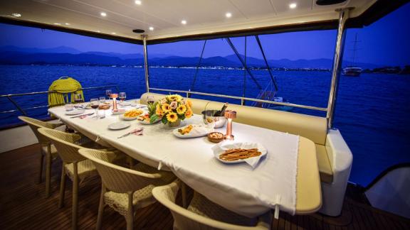 Among motor yacht rental options in Gocek Dalibay 2 aft deck shows dinner table setup and seating area in evening.
