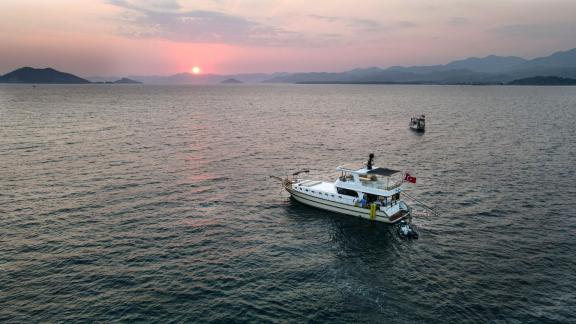 Among motor yacht rental options in Gocek Dalibay 2 is anchored at sea during sunset with islands in view.