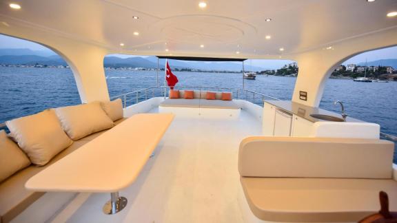 Among motor yacht rental options in Gocek Dalibay 2 upper deck seating area with sea view is seen onboard.