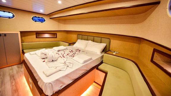 Among motor yacht rental options in Gocek Dalibay 2 cabin shows double bed and side seating area for comfort.