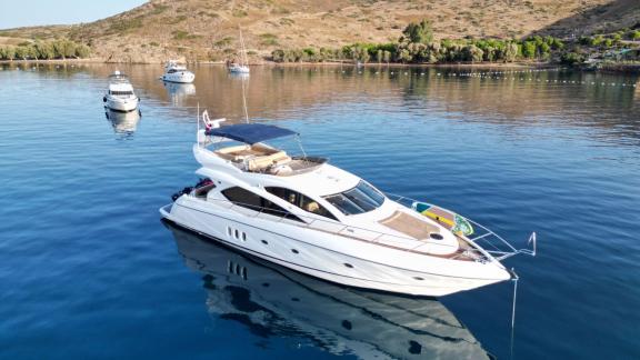 The Distraction motor yacht is anchored in calm water, waiting in a peaceful setting.