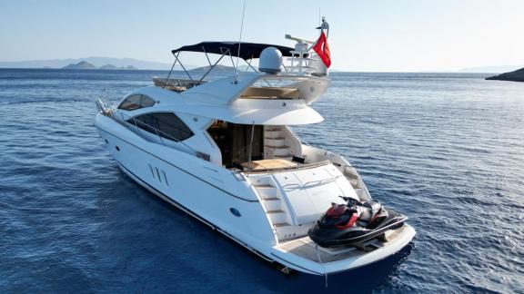 The Distraction motor yacht is anchored at sea, equipped with a jet ski on the aft deck.