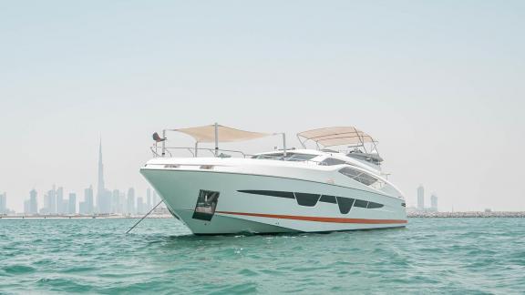 The yacht Dolce Vita is anchored at sea, showcasing elegance with a city backdrop.