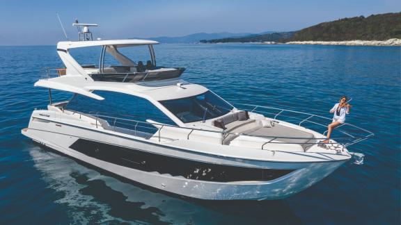 The motor yacht Emilia 2 showcases its luxurious design with a person enjoying the sun on the sea.