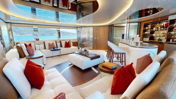 The stylish salon on Eternal Spark features a modern bar and spacious seating for luxury yacht charter guests.