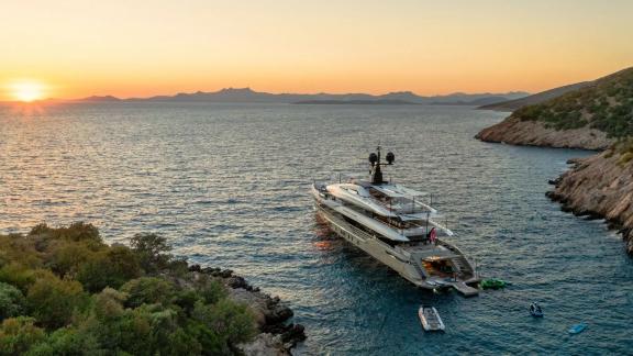 Eternal Spark motor yacht is anchored in a calm bay at sunset during an exclusive yacht charter holiday.