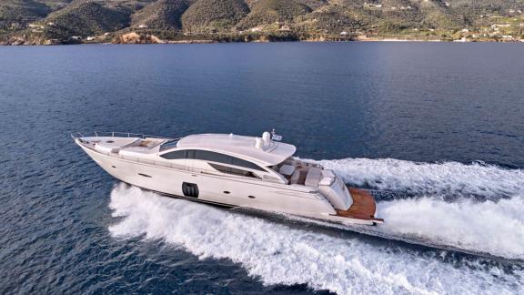 The For Ever yacht cruising fast at sea with a beautiful coastal view in the background.