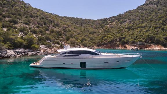 Die Luxusyacht For Ever liegt vor Anker im blauen Wasser einer grünen Bucht.