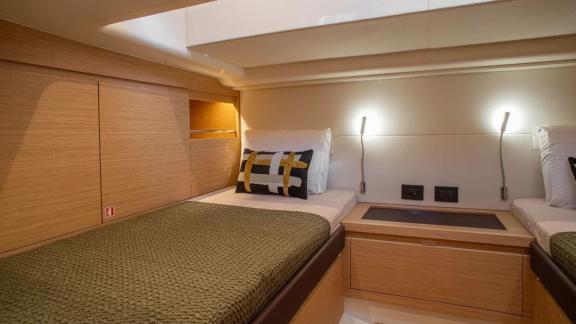 Among Saint Tropez yacht charter options Fortitude motor yacht shows cabin with two beds and central storage unit.