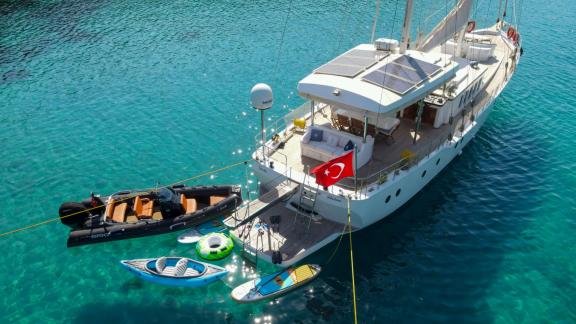 The luxury gulet Gazella is anchored off the coast of Bodrum. Nearby are a speedboat, a paddleboard, and inflatable wate