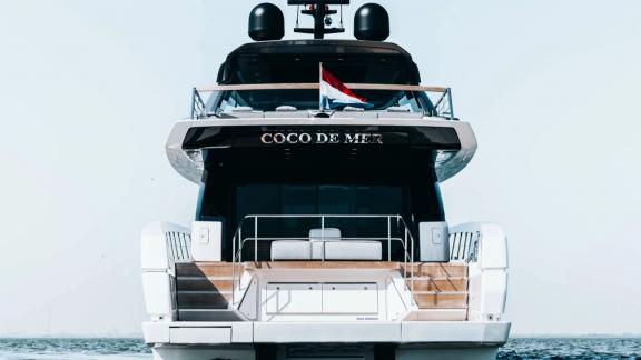 The aft section of motor yacht Coco De Mer stands out with its elegant design and flag detail.