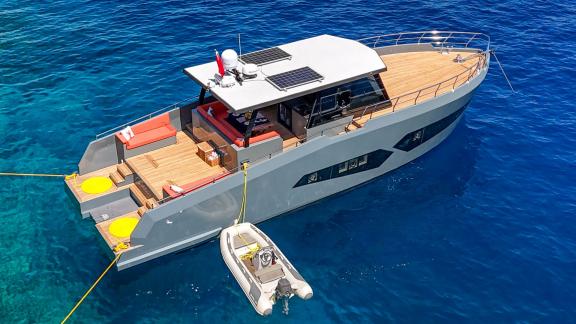 Aerial view of the Gottiri motor yacht with a small boat and blue waters beside it.