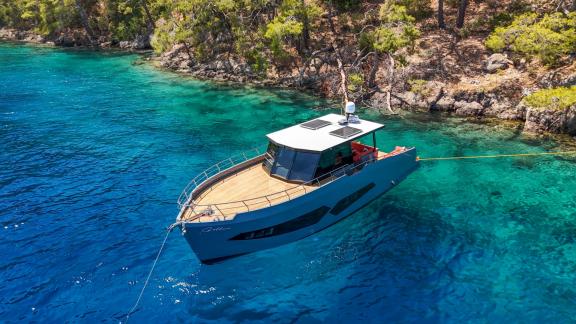 Die Motoryacht Gottiri über kristallklarem blauen Wasser in einer Bucht, von oben gesehen.