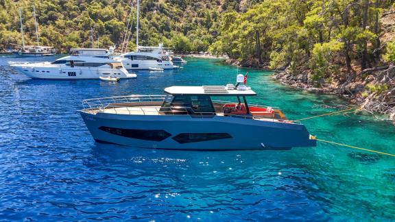 The Gottiri motor yacht is anchored in a cove with other boats, surrounded by green trees.