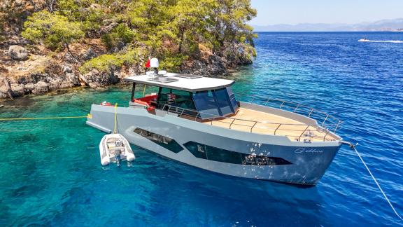 The Gottiri motor yacht is anchored in a cove with clear water, showcasing nature's tranquility.