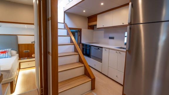 The modern galley on the Gottiri motor yacht is complemented by white cabinets and a staircase.