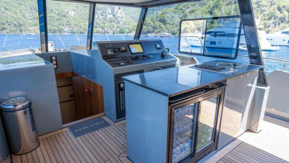 The captain's bridge and bar area on the Gottiri motor yacht feature modern equipment and a drinks fridge.