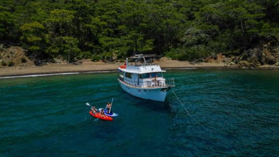 Grainne Mhaol trawler yat, sakin bir koyda demirlemiş ve misafirler su oyuncakları ile keyifli vakit geçiriyor.