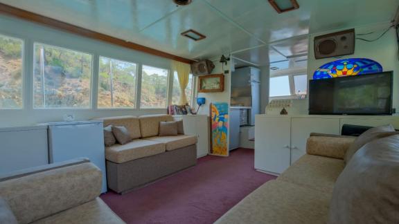 Cozy seating area on the trawler Grainne Mhaol with nature views through large windows.