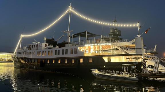 Die Motoryacht Harmony II liegt nachts beleuchtet im Hafen vor Anker.