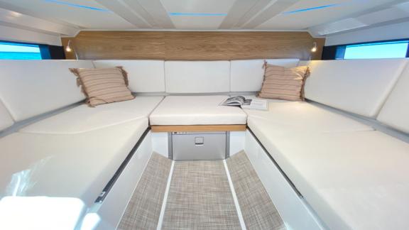 Spacious and comfortable seating area inside motor yacht Ikigai, decorated with white cushions.