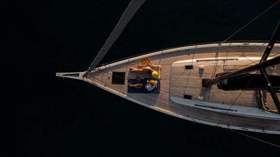 Luftaufnahme der Passagiere, die auf dem Vorderdeck der Izanami Yacht die Sonne mit Meerblick genießen.